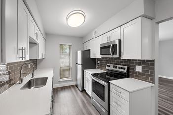 an empty kitchen with white cabinets and stainless steel appliances